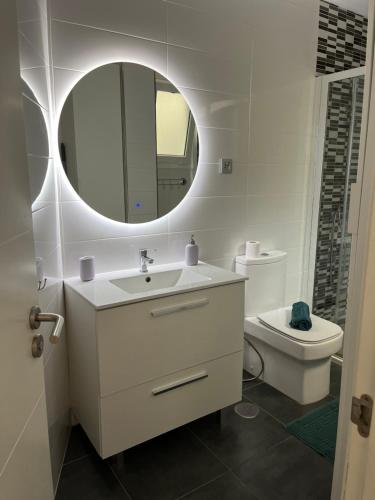 a bathroom with a sink and a mirror and a toilet at Yudelmys confort in Las Palmas de Gran Canaria