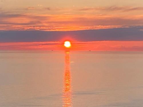 a sunset over the ocean with the sun reflecting in the water at Torra di Ciocce in Pino