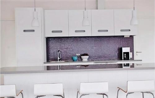 a kitchen with white cabinets and white chairs at Gorgeous Home In Vaggeryd With Wifi in Vaggeryd
