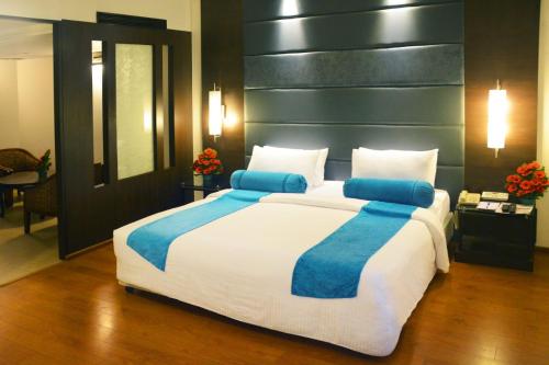 a large bed with blue pillows in a bedroom at Ashraya International Hotel in Bengaluru