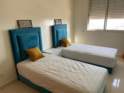 アガディールにあるLuxuswohnung mit tollen Meerblickのブルーヘッドボード付きのベッド2台が備わる客室です。
