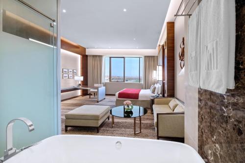 a hotel room with a tub and a bedroom at Grand Millennium Tabuk in Tabuk
