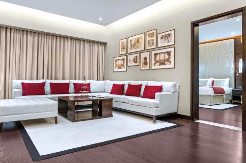 a living room with a white couch and red pillows at Grand Millennium Tabuk in Tabuk