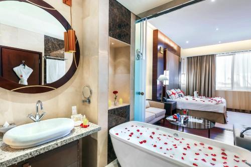 a bathroom with a bath tub and a bedroom at Grand Millennium Tabuk in Tabuk
