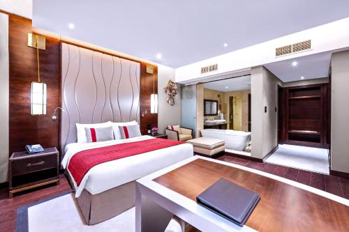 a hotel room with a large bed and a desk at Grand Millennium Tabuk in Tabuk