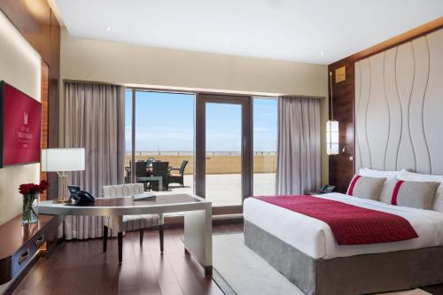a hotel room with a bed and a desk with a view at Grand Millennium Tabuk in Tabuk