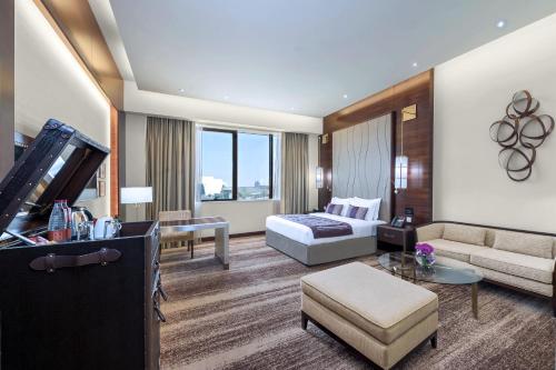 a hotel room with a bed and a couch at Grand Millennium Tabuk in Tabuk
