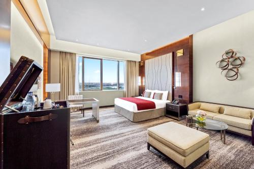 a hotel room with a bed and a couch at Grand Millennium Tabuk in Tabuk