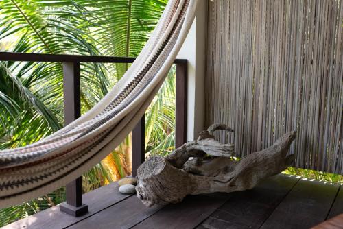 a hammock on a porch with a palm tree at Casa Mariposa Beach Hotel in Tierra Blanca