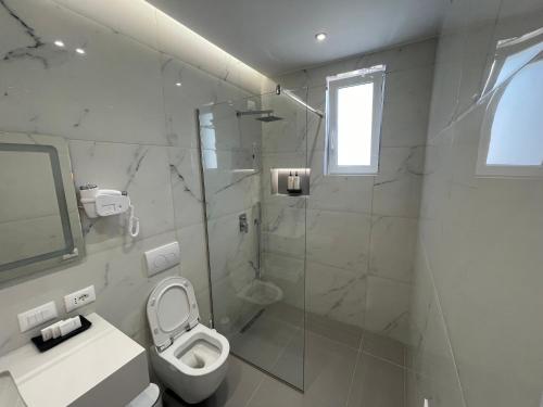 a white bathroom with a shower and a toilet at Seaside Hotel in Vlorë
