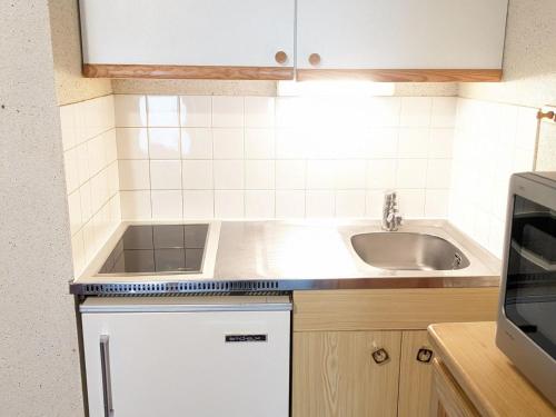 une petite cuisine avec un évier et un micro-ondes dans l'établissement Studio confortable avec balcon et casier à skis - FR-1-557-111, à Les Adrets
