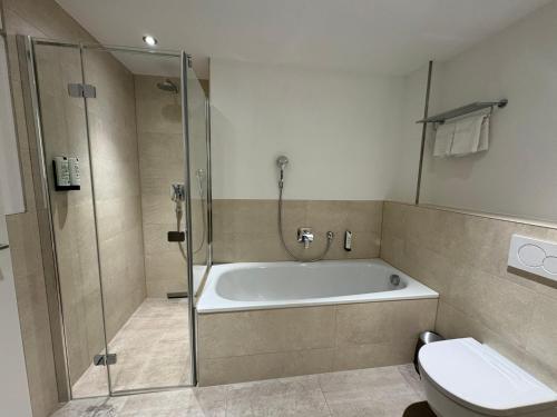 a bathroom with a bath tub and a toilet at Fontane Hotel in Schorfheide