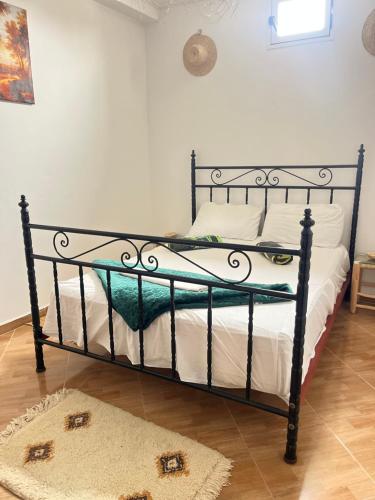 a bed with a black frame in a room at Let Us Surf in Tamraght Ouzdar