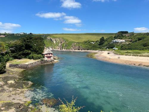 a view of a beach with a small building in the water at Little Highfield in Kingsbridge
