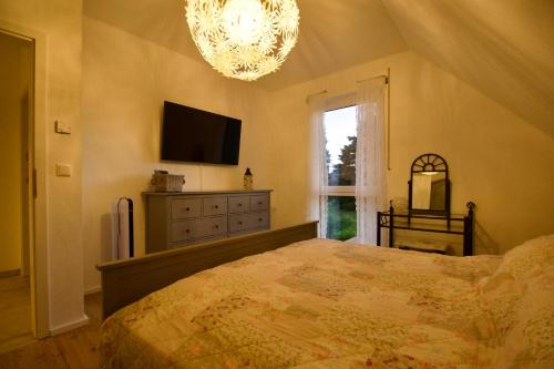 a bedroom with a bed and a television and a chandelier at Ferienhaus Plattenberg in Bad Oeynhausen