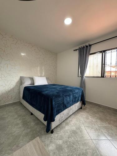 a bedroom with a bed with blue sheets and a window at Casa San Miguel 101 in Medellín
