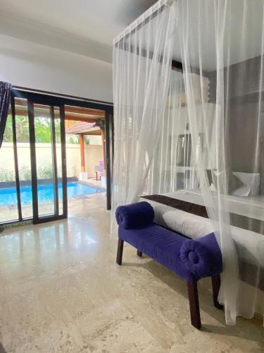 a bedroom with a canopy bed and a blue bench at One Bedroom Private Pool Classic Villa in Kuta