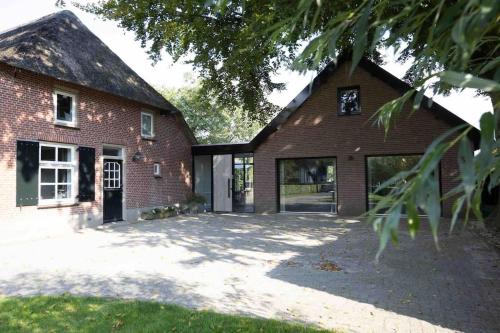 a red brick house with a large driveway at Gastenverblijf Studio 22 - woonboerderij in Haaren