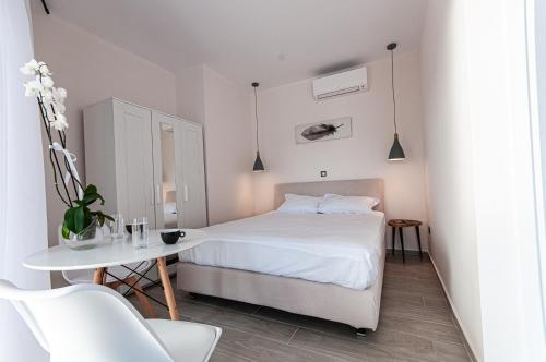 a white bedroom with a bed and a table at Boutique apartments Myesis in Samothráki