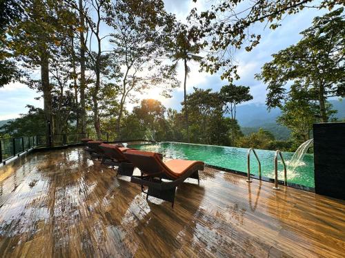 a pool with chairs on the deck of a resort at Viceroy Luxury Mountain Resort and Spa in Munnar