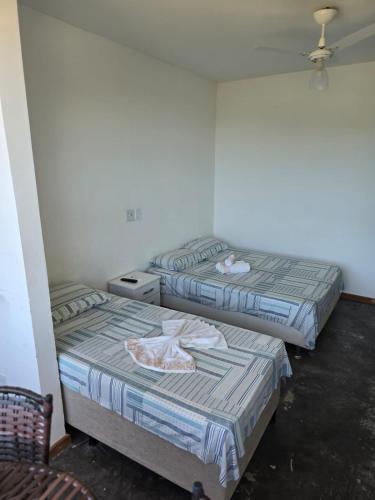 a room with two beds and a chair in it at Pousada Pé Na Areia in Arraial do Cabo