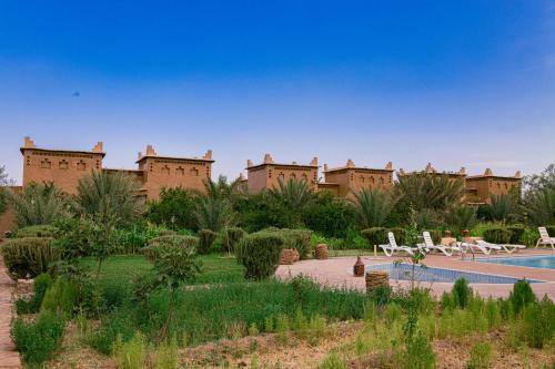 a resort with a swimming pool in front of a building at Maison D'h&ocirc;te Amridil in Skoura