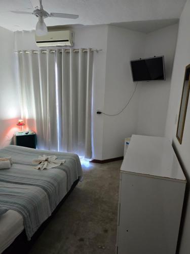 a bedroom with a bed and a flat screen tv at Pousada Pé Na Areia in Arraial do Cabo