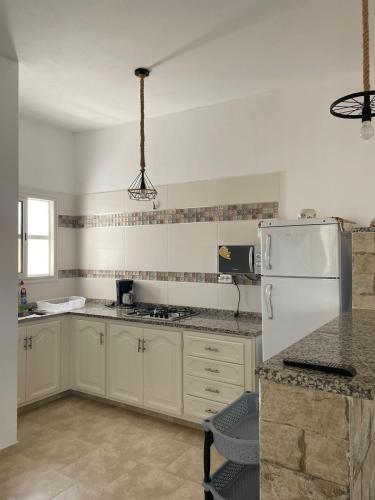 a kitchen with white cabinets and a white refrigerator at Résidence de la plage Ghar El Melh in Ghār al Milḩ