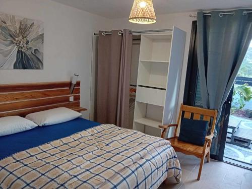 a bedroom with a bed and a chair and a window at Les terrasses in Sainte-Marie