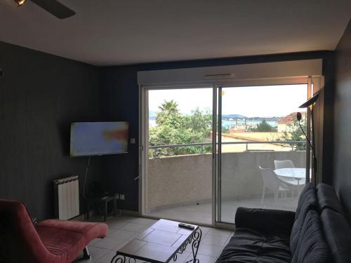 un salon avec un canapé et une porte coulissante en verre dans l'établissement Appartement T3 avec 2 chambres et grand balcon, à Sète