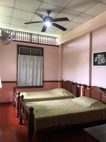 two beds in a bedroom with a ceiling fan at Baan Lotus Guest House in Phra Nakhon Si Ayutthaya