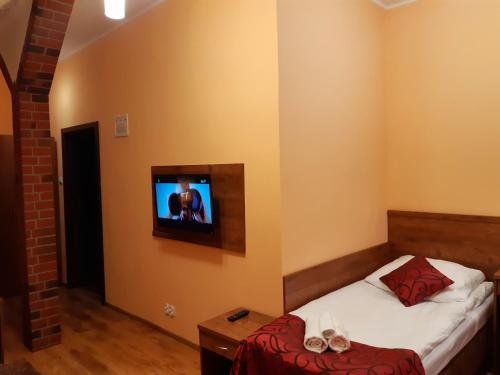 a bedroom with a bed and a tv on the wall at Pensjonat Zielone Wzgórze w Bolesławowie in Stronie Śląskie