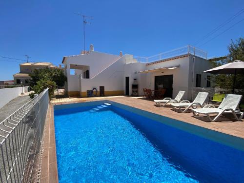 a villa with a swimming pool in front of a house at Casa Portela in Vila Nova De Cacela