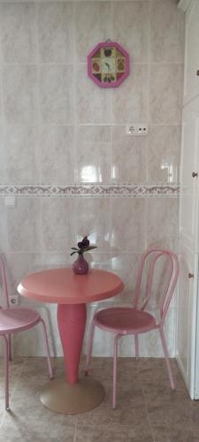 a pink table with two chairs and a table with a vase at Nuria's home in Calanda