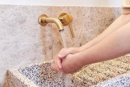 a person is drinking from a shower faucet at EQUILICUÁ in Agua Amarga