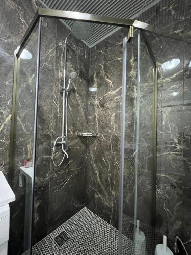 un bagno con doccia con parete in marmo nero di KERUEN SARAY APARTMENTs 20-1 a Türkistan