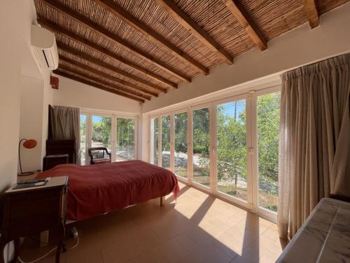 een slaapkamer met een rood bed en grote ramen bij Villa Horta do Limão 8-10 pessoas a 4 km das praias da Ria Formosa Fuseta in Moncarapacho