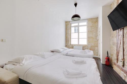 Cette chambre comprend 2 lits blancs et une télévision. dans l'établissement le zebre, à Paris