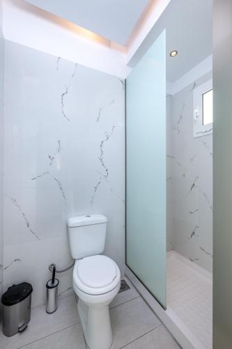 a white bathroom with a toilet and a shower at Patricia Suites in Faliraki