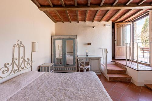 um quarto com uma cama, uma secretária e uma janela em Fattoria Pieve a Salti em Buonconvento