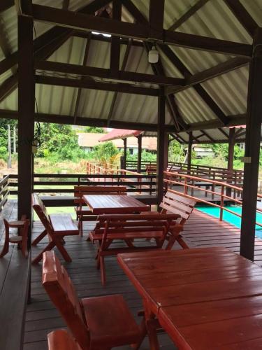 a deck with wooden tables and chairs and a pool at Baan Lotus Guest House in Phra Nakhon Si Ayutthaya