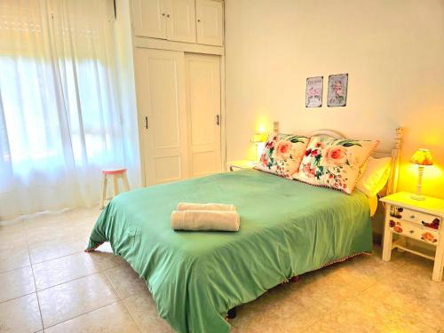 a bedroom with a green bed with a towel on it at ALBAREÍLLA by #cherrygredos in El Arenal