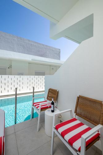 a balcony with two chairs and a swimming pool at Patricia Suites in Faliraki