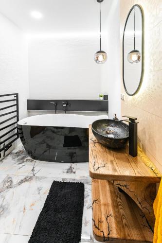 a bathroom with a black tub and a sink at Luxapart Golf Ostravice in Ostravice