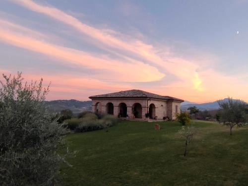 a building in a field with a sunset in the background at Villa Liliana, Exclusive Property in Monte Rinaldo