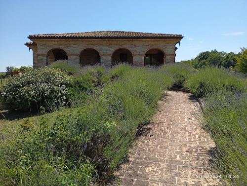 an old brick building on a grassy hill with a dirt road at Villa Liliana, Exclusive Property in Monte Rinaldo
