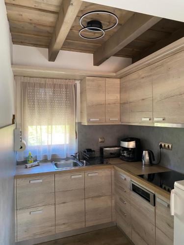 a kitchen with wooden cabinets and a sink and a window at Ábrahámhegyi Nyaralóház in Ábrahámhegy