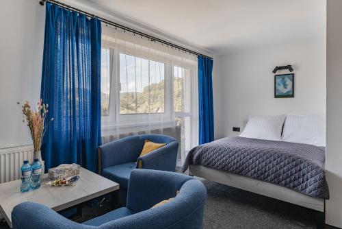 a bedroom with blue chairs and a bed and a window at Apartamenty Sielska 102 in Szlachtowa
