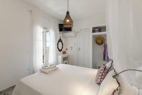 a white bedroom with a white bed and a window at Margarita Studios Ambelas in Ambelas