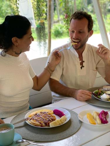 Ban Madua WanMY HOME Resort - Koh phangan vacation house rentals的坐在餐桌旁吃饭的男人和女人